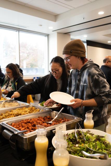 Two students at the ASI Food Pantry's Friendsgiving Feast scooping freshly mashed garlic potatoes.
